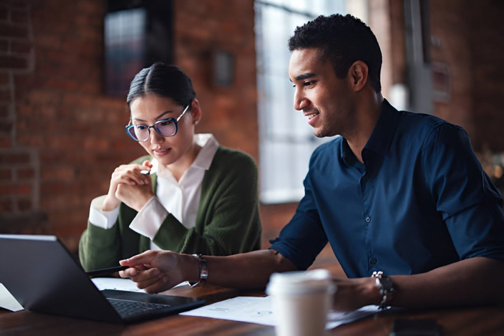 two employees using a laptop while collaborating
