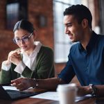 two employees using a laptop while collaborating